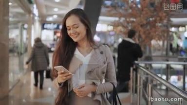 <strong>购物袋</strong>谈在购物中心电话微笑的女人。智能手机在购物中心的漂亮女孩.